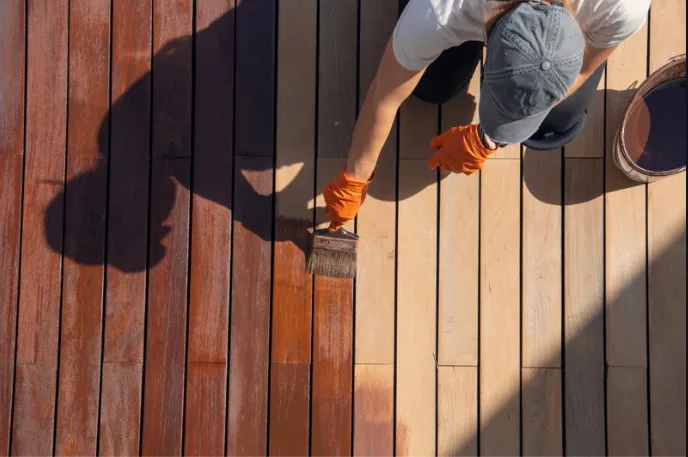Worker staining deck boards during a deck sealing project